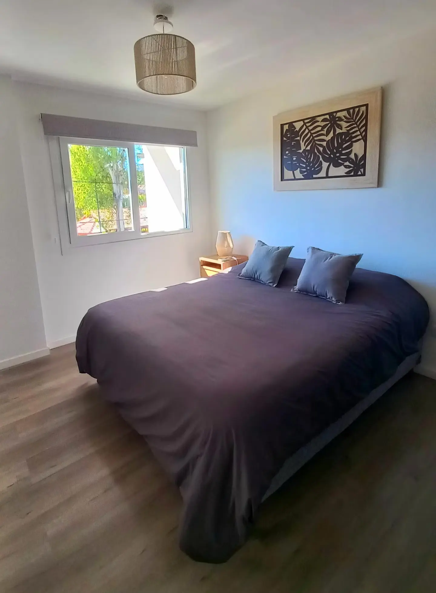 Dormitorio con cama matrimonial y cuadro de hojas